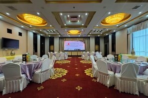 A conference room with round tables, chairs, a projector screen, and a large screen displaying a presentation. - Taiyuan Water Conservancy Building Finance University North Campus Store (Taiyuan)