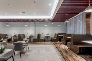 Un interior moderno con arreglos de asientos y mesas, una pared de acento de madera e iluminación colgante.