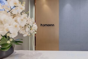 Un área de recepción con mostrador, una planta en maceta y un letrero con el nombre 'homeinn'.