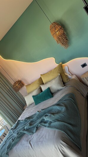Experience the unique ceiling design and cozy ambiance of this stylish bedroom, featuring a plush bed and natural decor elements.