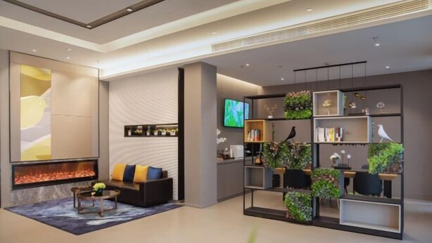 A modern living room with a fireplace, a sofa, a coffee table, and a bookshelf with plants. - Homeinn Selected Hotel (Suzhou North Railway Station Cailian Plaza) (Suzhou)