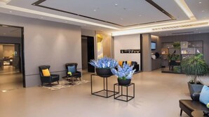 A modern hotel lobby with a minimalist design, featuring a reception desk, seating area with sofas, and decorative plants. - Homeinn Selected Hotel (Suzhou North Railway Station Cailian Plaza) (Suzhou)