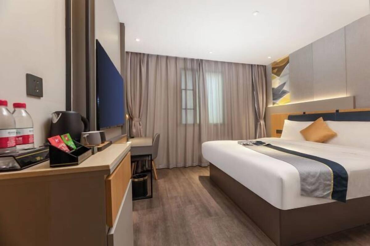 Habitación de hotel con cama, escritorio y un espejo grande.