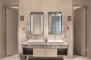 Une salle de bain avec deux lavabos, des miroirs et un meuble-lavabo avec des tiroirs.