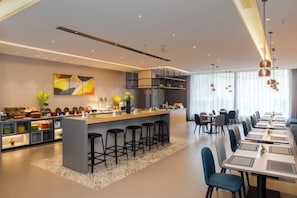 A modern hotel dining area with a central island, bar stools, and a long table with chairs. - Homeinn Selected Hotel (Suzhou North Railway Station Cailian Plaza) (Suzhou)