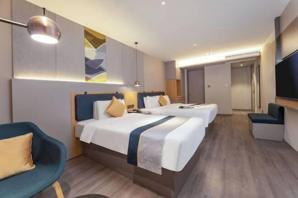 Una habitación de hotel con dos camas, un escritorio, una silla y un televisor.