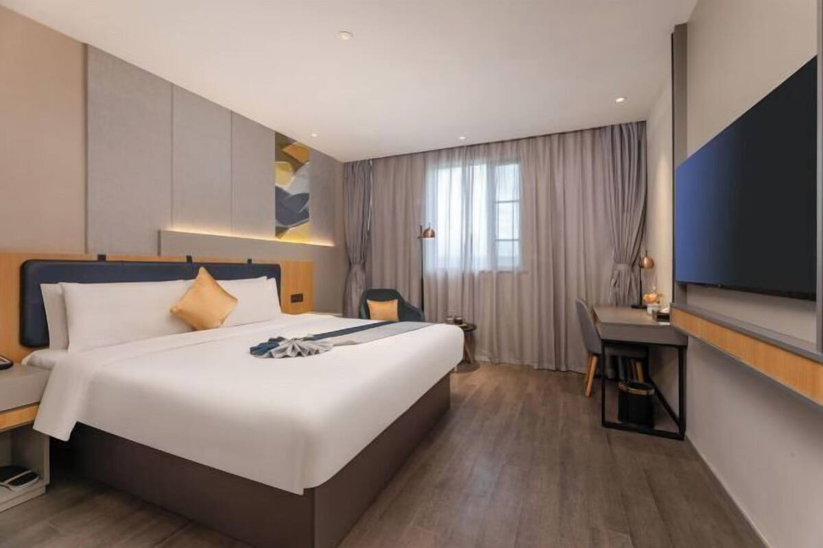 Una habitación de hotel moderna con una cama grande, un escritorio y un televisor.