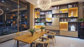 A modern interior with a wooden dining table, chairs, and a large bookshelf filled with books and decorative items.