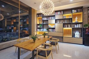 A modern interior with a wooden dining table, chairs, and a large bookshelf filled with books and decorative items. - Lizun Select Hotel (Hebi Liyang Road Branch) (Hebi)