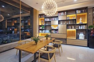 Un interior moderno con una mesa de comedor de madera, sillas y una amplia estantería llena de libros y objetos decorativos.