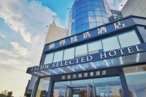 Un hotel con fachada de vidrio moderna y señalización que indica que es 'LIZUN SELECTED HOTEL'.