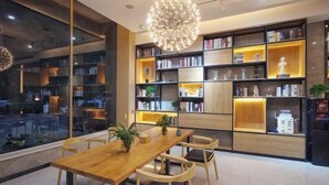Una biblioteca moderna con una mesa y sillas de madera, estanterías y un candelabro decorativo.