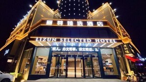 Un hotel con un cartel llamativo que dice "LIZUN SELECTED HOTEL" y una gran estructura en forma de cúpula iluminada sobre la entrada.