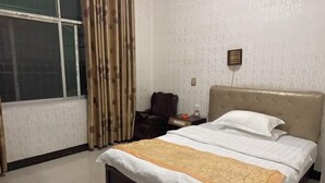 Habitación de hotel con cama, mesita de noche, silla y ventana con cortinas.