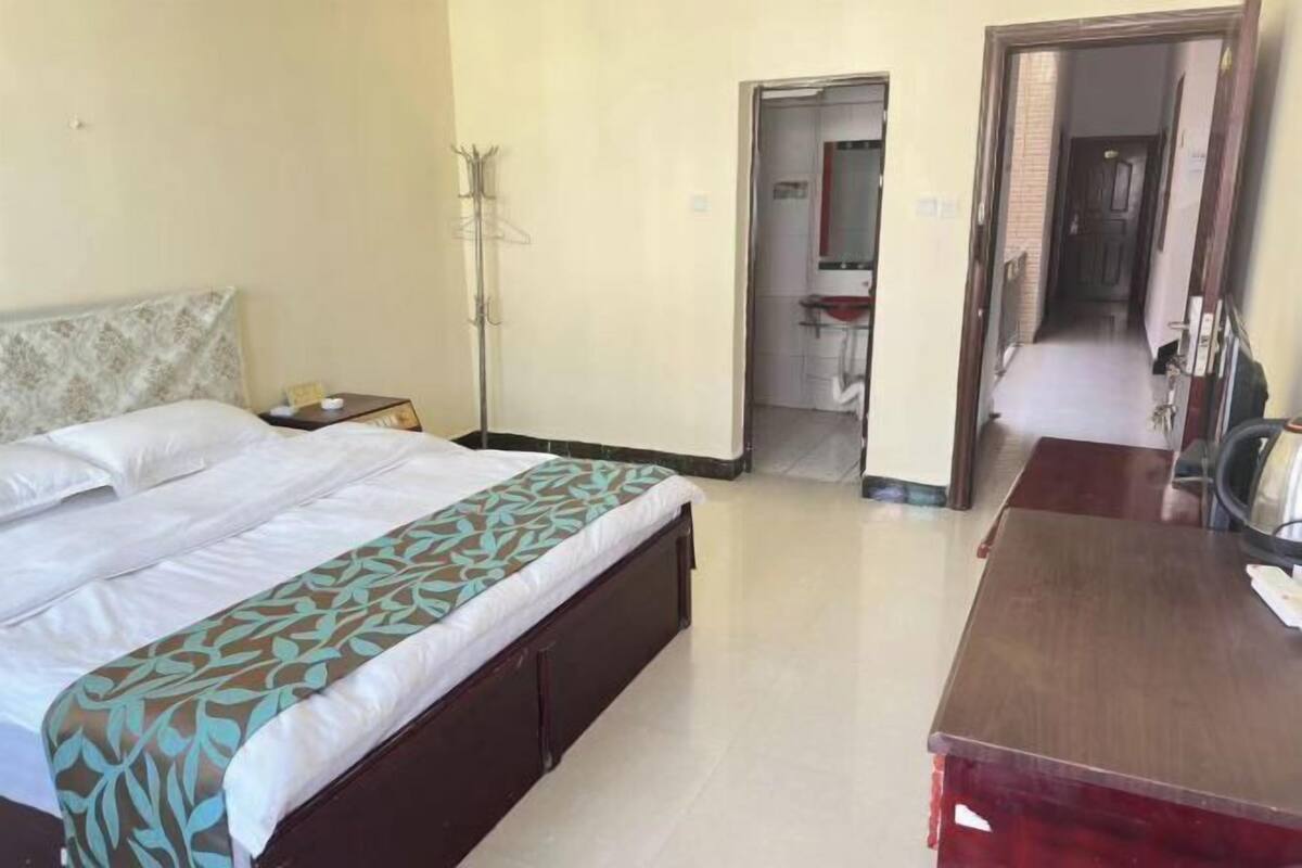 Um quarto com cama, mesa de cabeceira e escrivaninha.