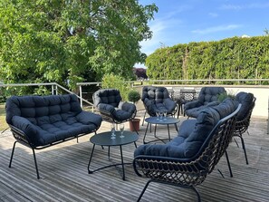 Un espace extérieur aménagé avec des chaises confortables et une petite table, entouré de verdure et sous un ciel dégagé.