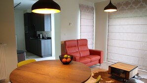 Ein modernes Wohnzimmer mit einem runden Holztisch, einem roten Ledersofa und einem kleinen Beistelltisch.