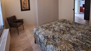 Ein Schlafzimmer mit Bett, Stuhl, Kleiderschrank und Klimaanlage.