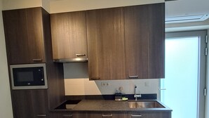 Eine moderne Küche mit dunklen Holzschränken, einer eingebauten Mikrowelle und einer Edelstahlspüle.