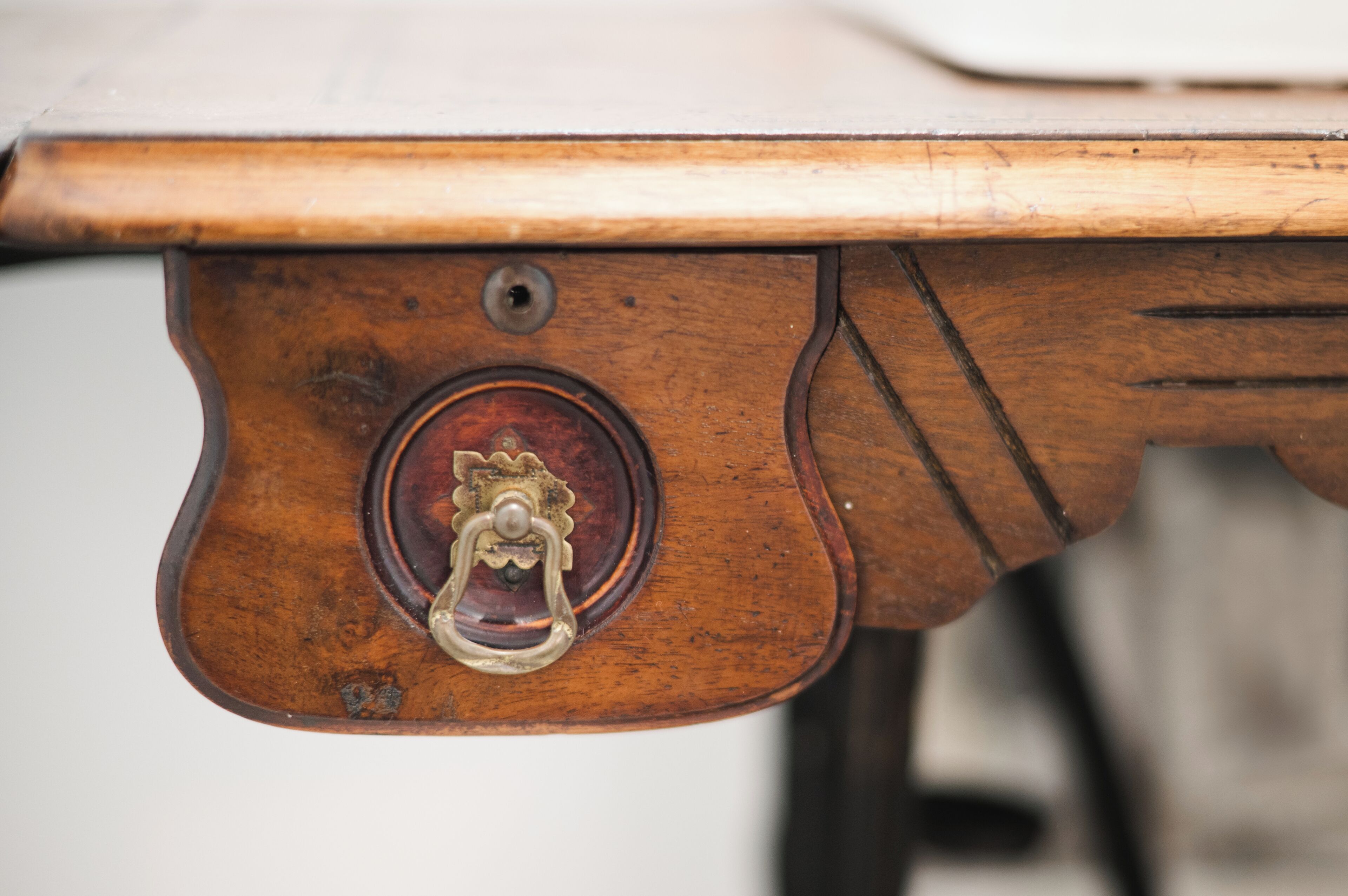 A close-up of a wooden table with a metal handle and a circular inlay.