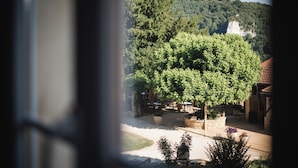 A courtyard with outdoor seating, surrounded by trees and a mountain backdrop. - Domaine de Malet (Vitrac)