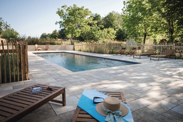 Une piscine avec des chaises longues et un transat.