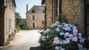 A narrow street with stone buildings, a clear sky, and a distant house. - Domaine de Malet (Vitrac)