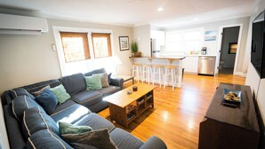 Un salon moderne avec un canapé, une table basse et un coin cuisine à l’arrière-plan.