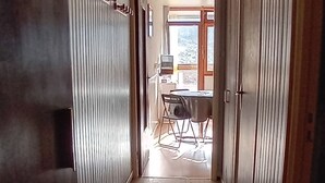 Un estrecho pasillo con piso de baldosas que conduce a un comedor con una mesa y sillas.