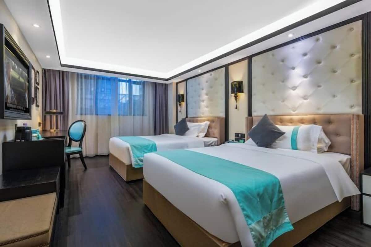 A hotel room with two beds, a desk, and a chair.