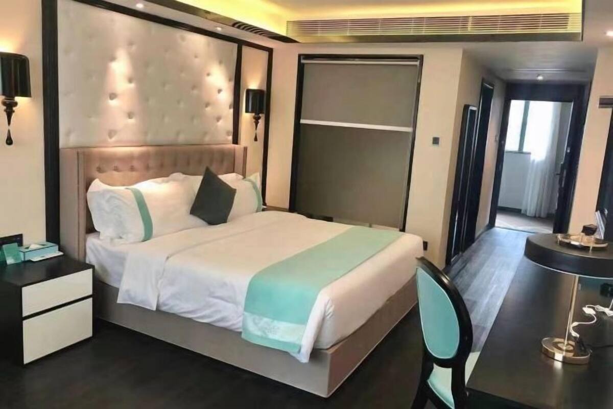 A hotel room with a large bed, a desk, and a chair.