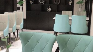 Comedor con sillas tapizadas en azul claro y una pared negra decorada.