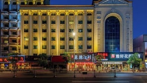 Un hotel grande con varios pisos, una entrada arqueada destacada y señalización iluminada.