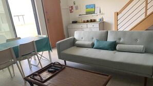 Ein Wohnzimmer mit einer Couch, einem Couchtisch, einem Esstisch mit Stühlen und einer Treppe.