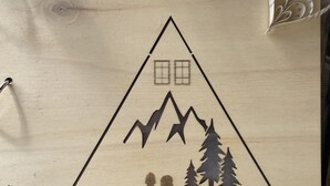 Une enseigne en bois représentant la silhouette d’une montagne et d’un arbre, avec le texte « RÉSIDENCE SANTA LUCIA ».