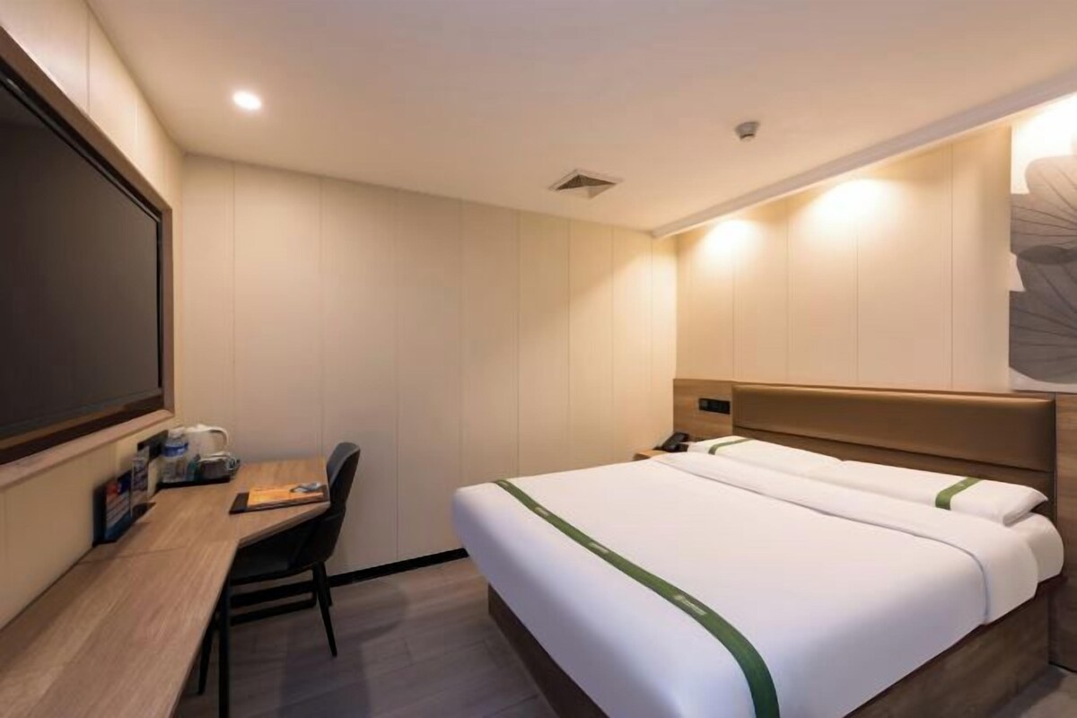 A hotel room with a bed, a desk, and a chair.
