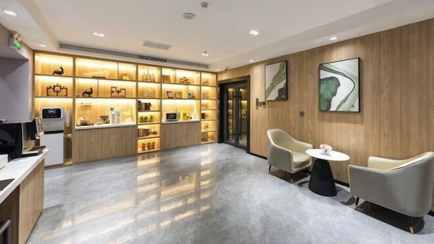 Rebost d'hotel modern amb un sòl de marbre brillant, una taquilla d'estació i una presentació d'articles de luxe. Hi ha dues zones d'estar amb taules rodones i cadires actuals.