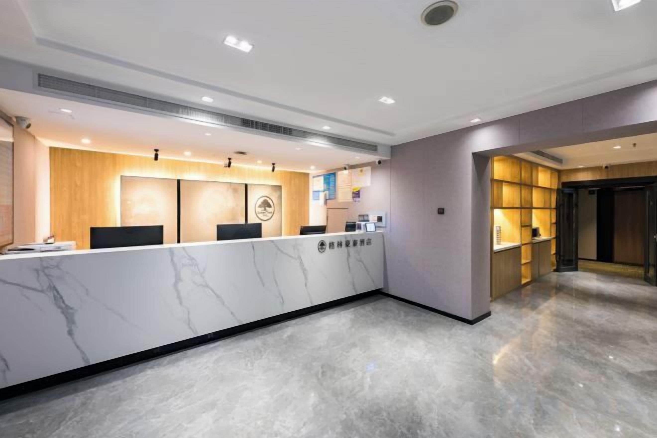 A hotel reception area with a marble counter, a wooden reception desk, and a modern interior design.