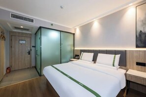 A hotel room with a large bed, a wardrobe, a bedside table, and a wall-mounted light. - GreenTree Inn Smart Choice Hotel (Beijing West Railway Station north square) (Beijing)