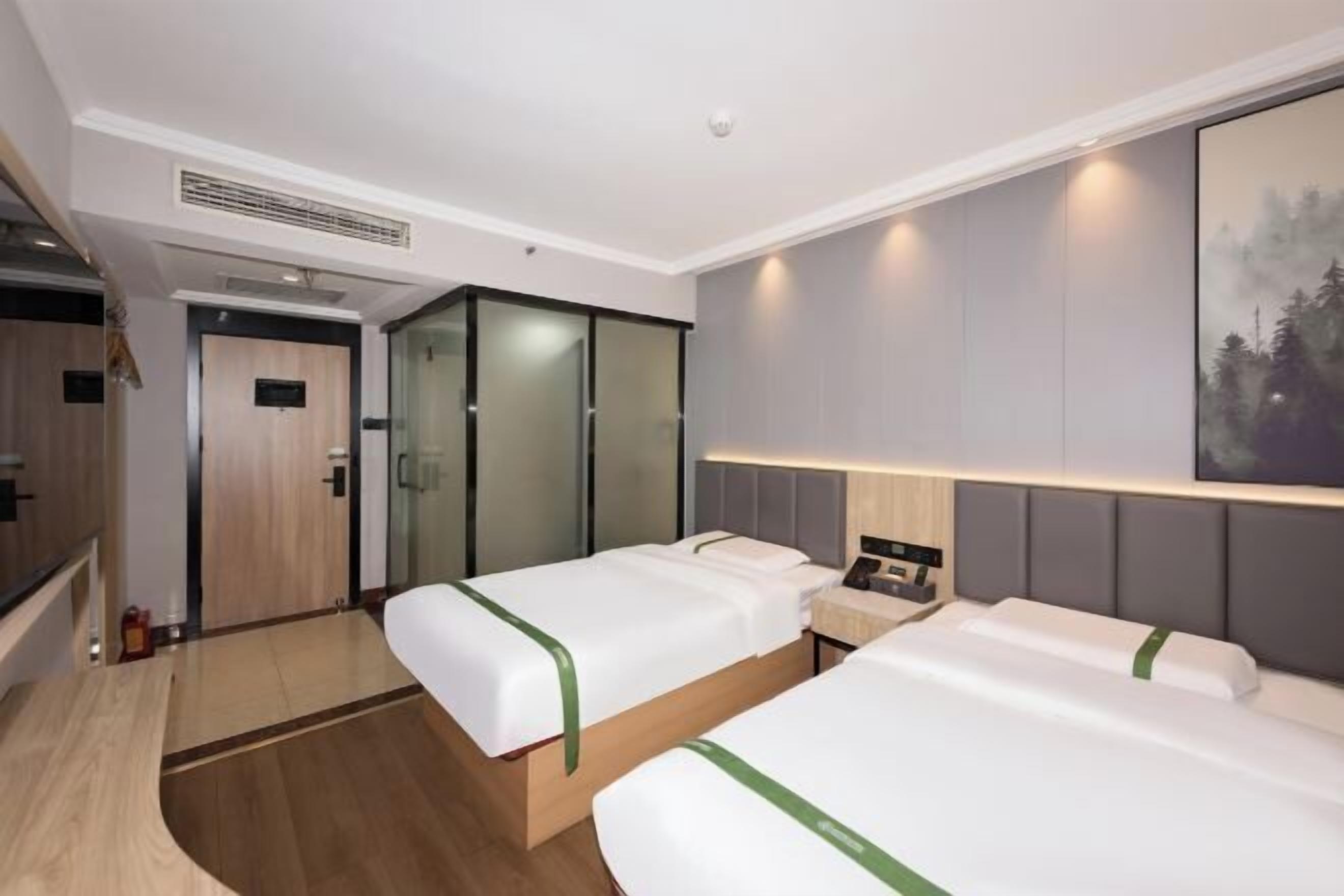 Une chambre d’hôtel avec deux lits, un bureau, un miroir et une armoire.