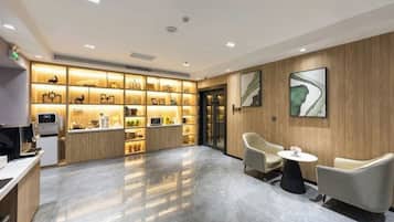 A hotel lobby with a reception desk, seating area, and a display of items on shelves.