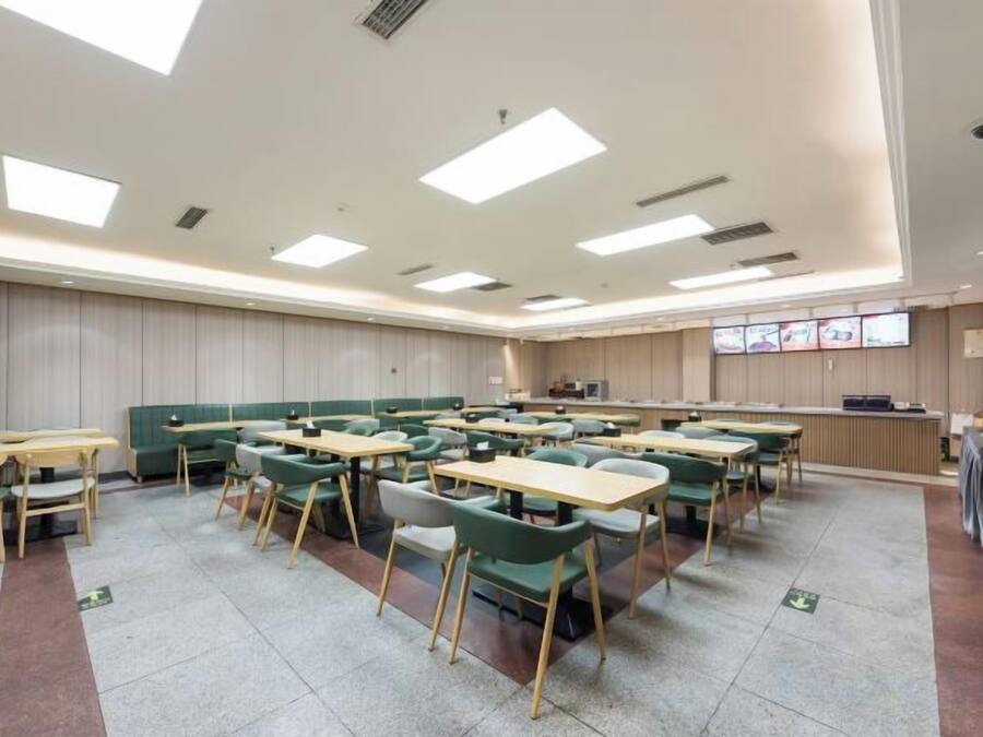 Una sala de conferencias con varias mesas y sillas, una mesa grande con una pizarra, y un mostrador de recepción.