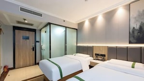 Habitació d'hotel amb dos llits, un armari, una taula de nit i un quadre a la paret.