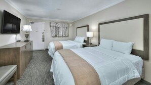 A hotel room with two beds, a TV, a desk, and a door. - Coral Beach 1022-Oceanfront 1BR-Pools-Lazy River (Myrtle Beach)