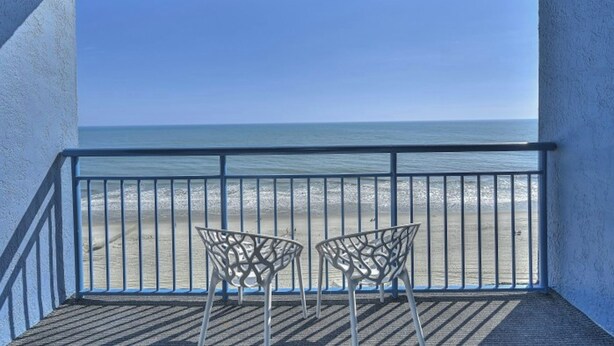A balcony with two chairs facing a beach. - Coral Beach 1022-Oceanfront 1BR-Pools-Lazy River (Myrtle Beach)