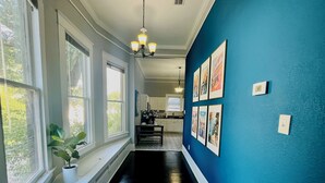 A hallway with a blue wall, a potted plant, and framed pictures.