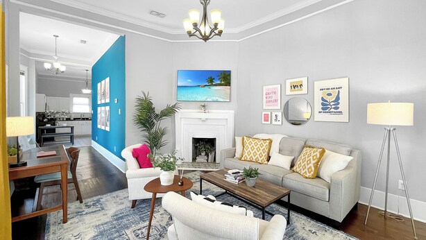 A living room with a fireplace, a dining area, and a kitchen in the background.