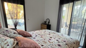 Un dormitorio con cama, mesita de noche y ventana con cortinas.