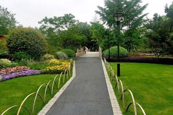 Un chemin qui traverse un jardin, avec un lampadaire et des garde-corps en métal de chaque côté.
