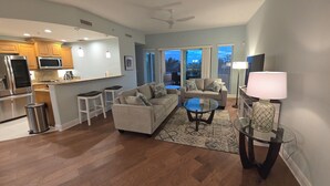 A modern living room with a sofa, coffee table, and a glass table with a lamp.